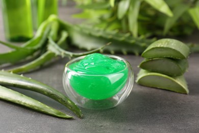 Photo of Bowl with natural gel and aloe vera leaves on grey table