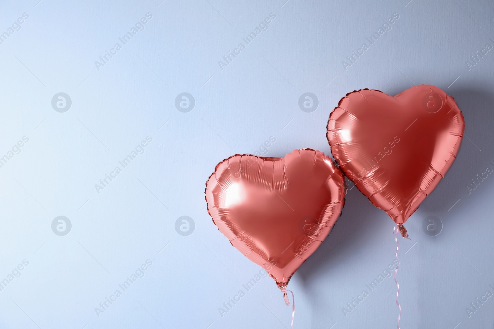 Photo of Heart shaped balloons near white wall. Space for text