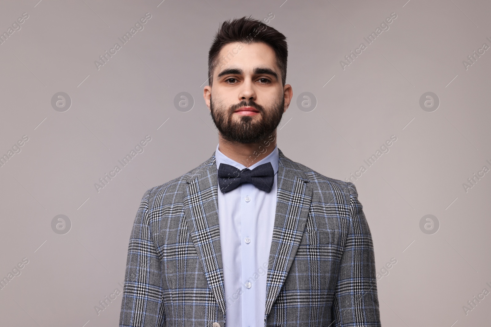 Photo of Portrait of handsome man in suit, shirt and bow tie on grey background