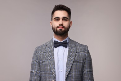 Photo of Portrait of handsome man in suit, shirt and bow tie on grey background
