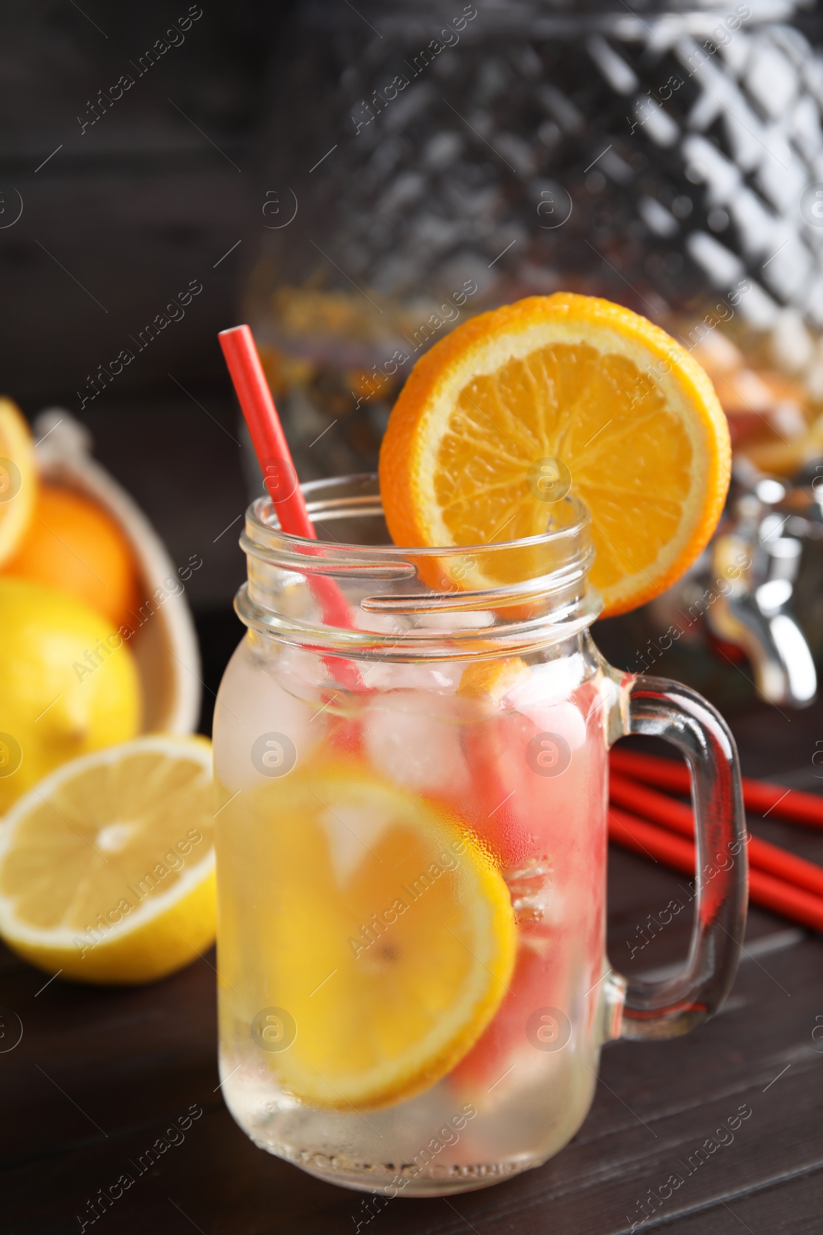 Photo of Delicious refreshing lemonade with orange slices in mason jar on wooden table