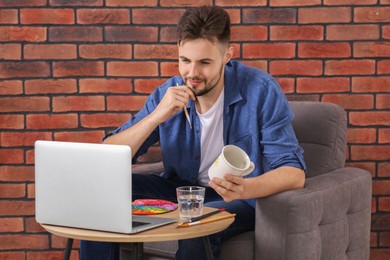Photo of Man learning to decorate cup while watching online course at home. Time for hobby