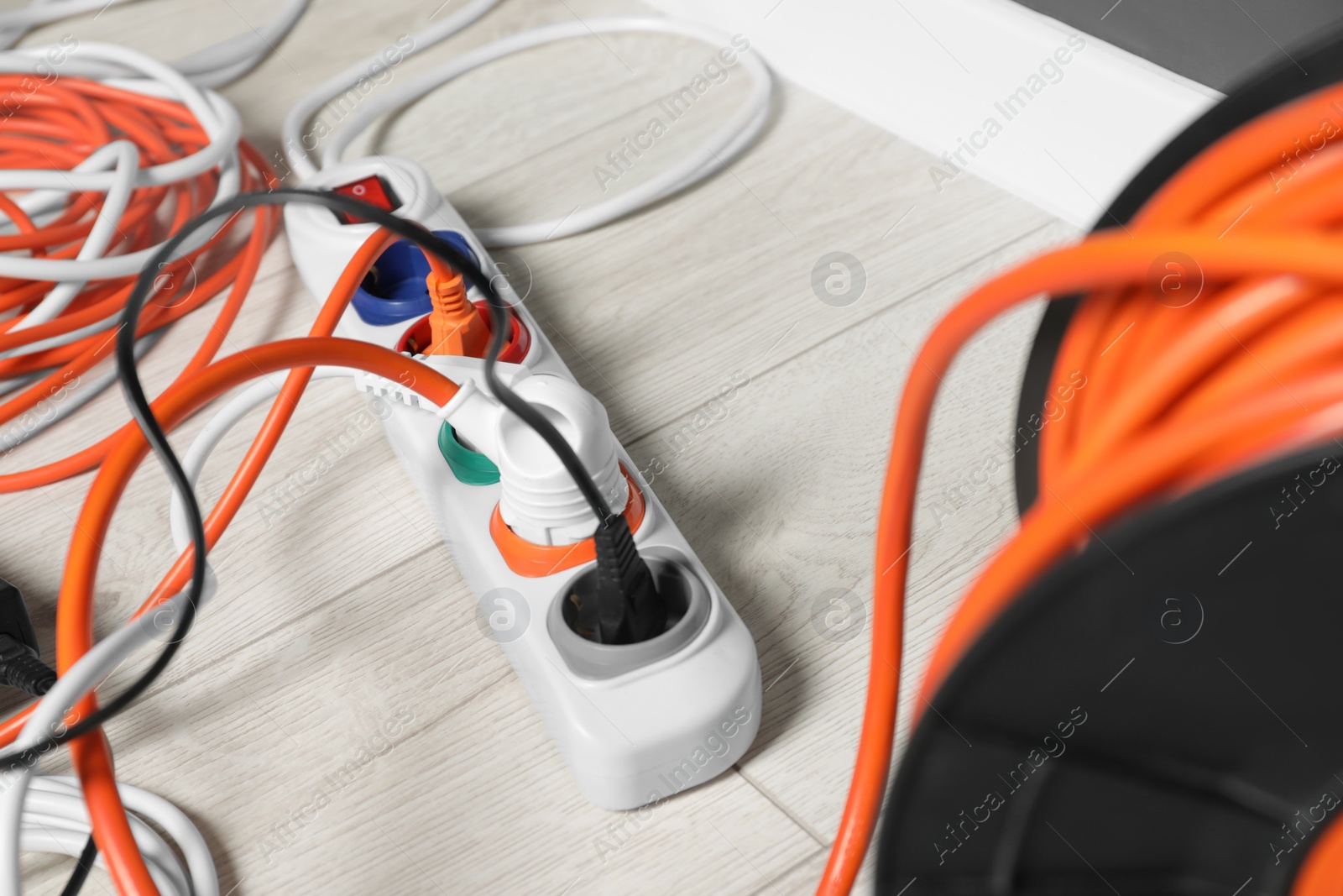 Photo of Power strip with different electrical plugs on white laminated floor, closeup