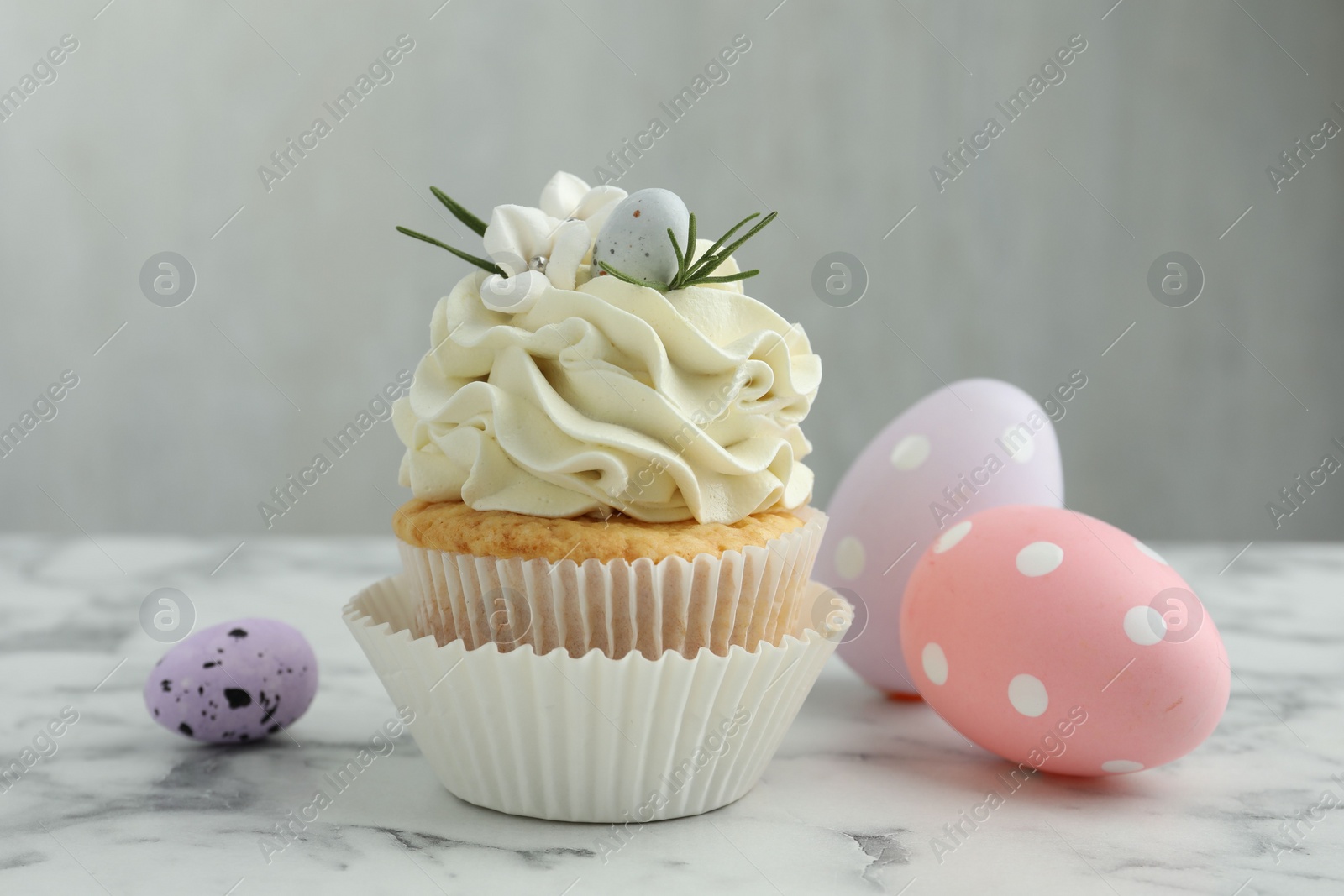 Photo of Tasty Easter cupcake with vanilla cream and eggs on white marble table