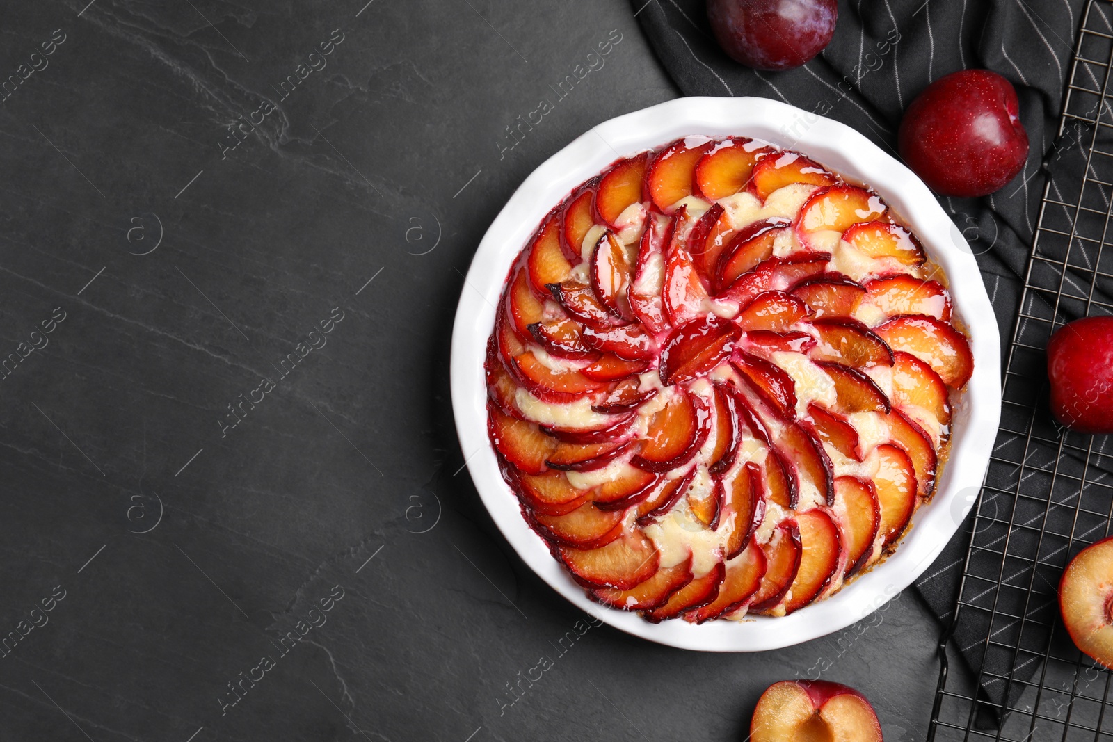 Photo of Delicious cake with plums on black table, flat lay. Space for text