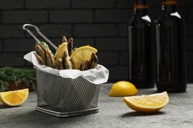 Delicious fried anchovies with slices of lemon on grey table. Space for text