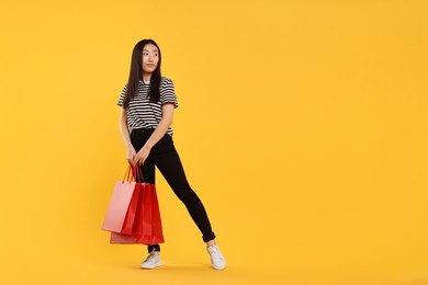 Photo of Beautiful woman with shopping bags on yellow background. Space for text