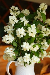 Bouquet of beautiful jasmine flowers in vase indoors, closeup