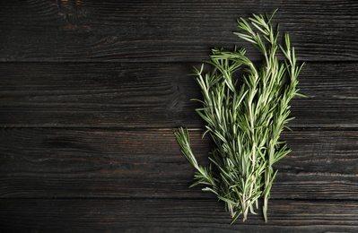 Photo of Fresh rosemary twigs on wooden table, top view. Space for text