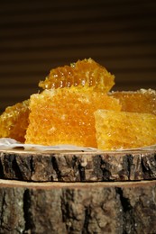 Photo of Natural honeycombs on stump against blurred background, closeup