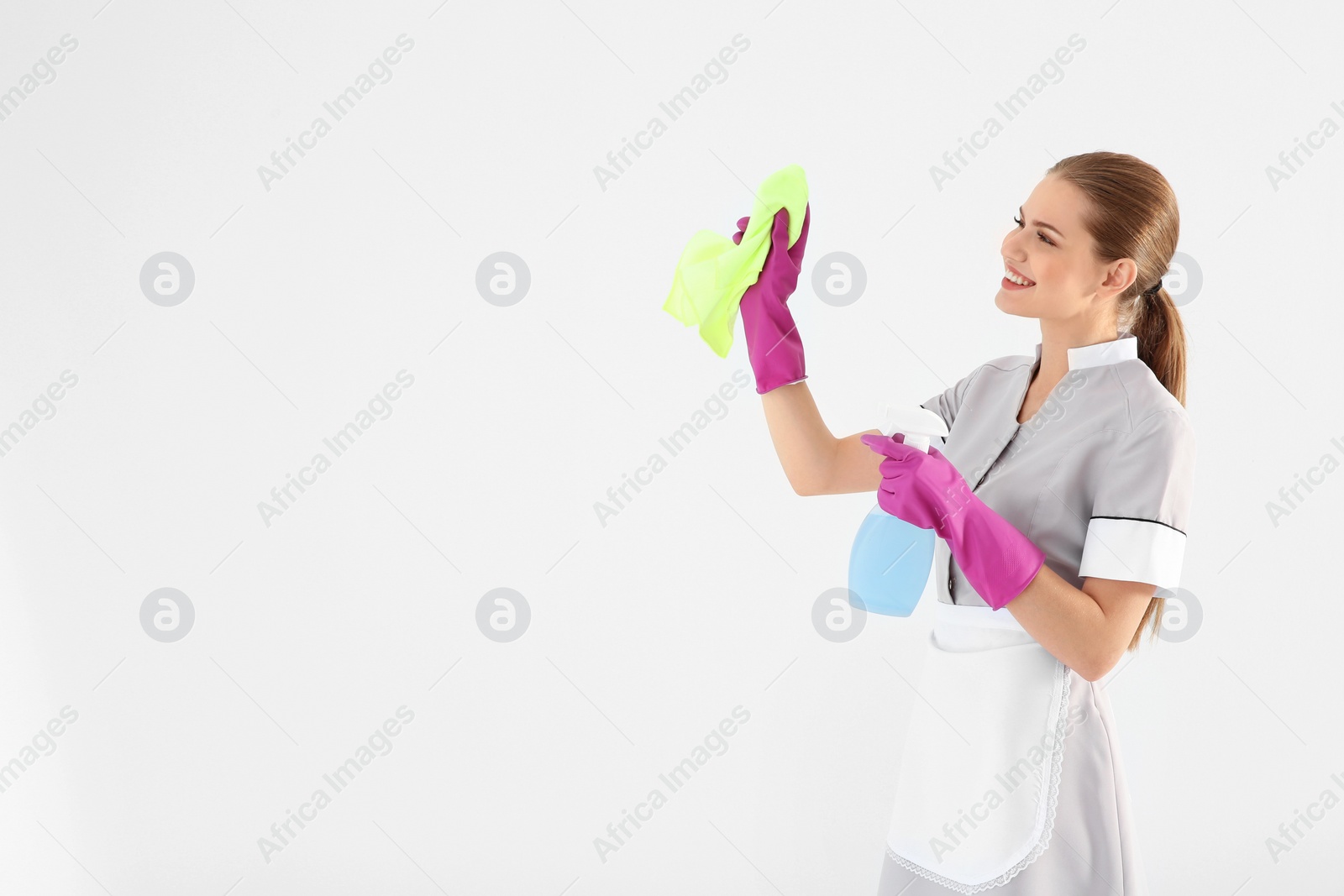 Photo of Young chambermaid with rag and detergent on white background