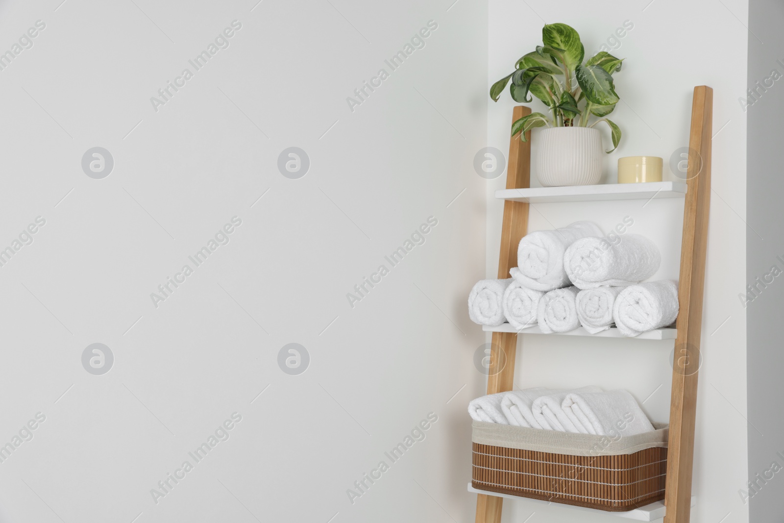 Photo of Soft towels on decorative ladder near white wall, space for text