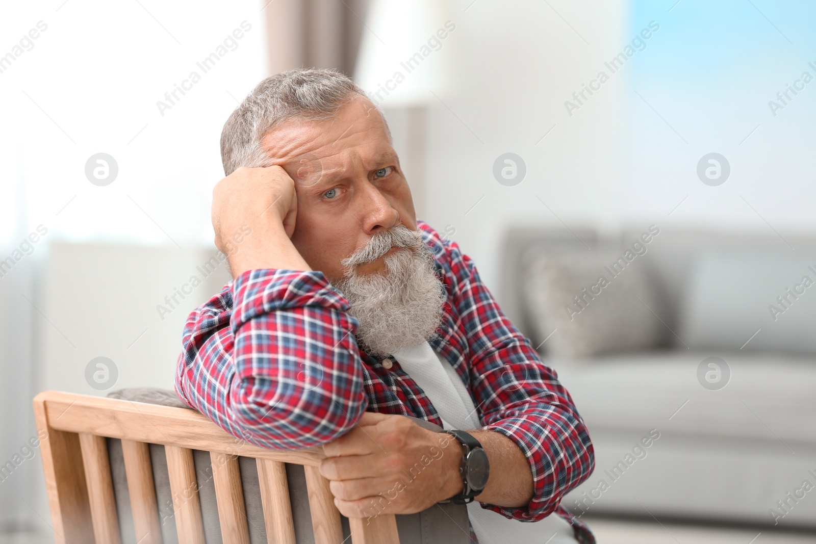 Photo of Portrait of handsome mature man sitting on chair in room