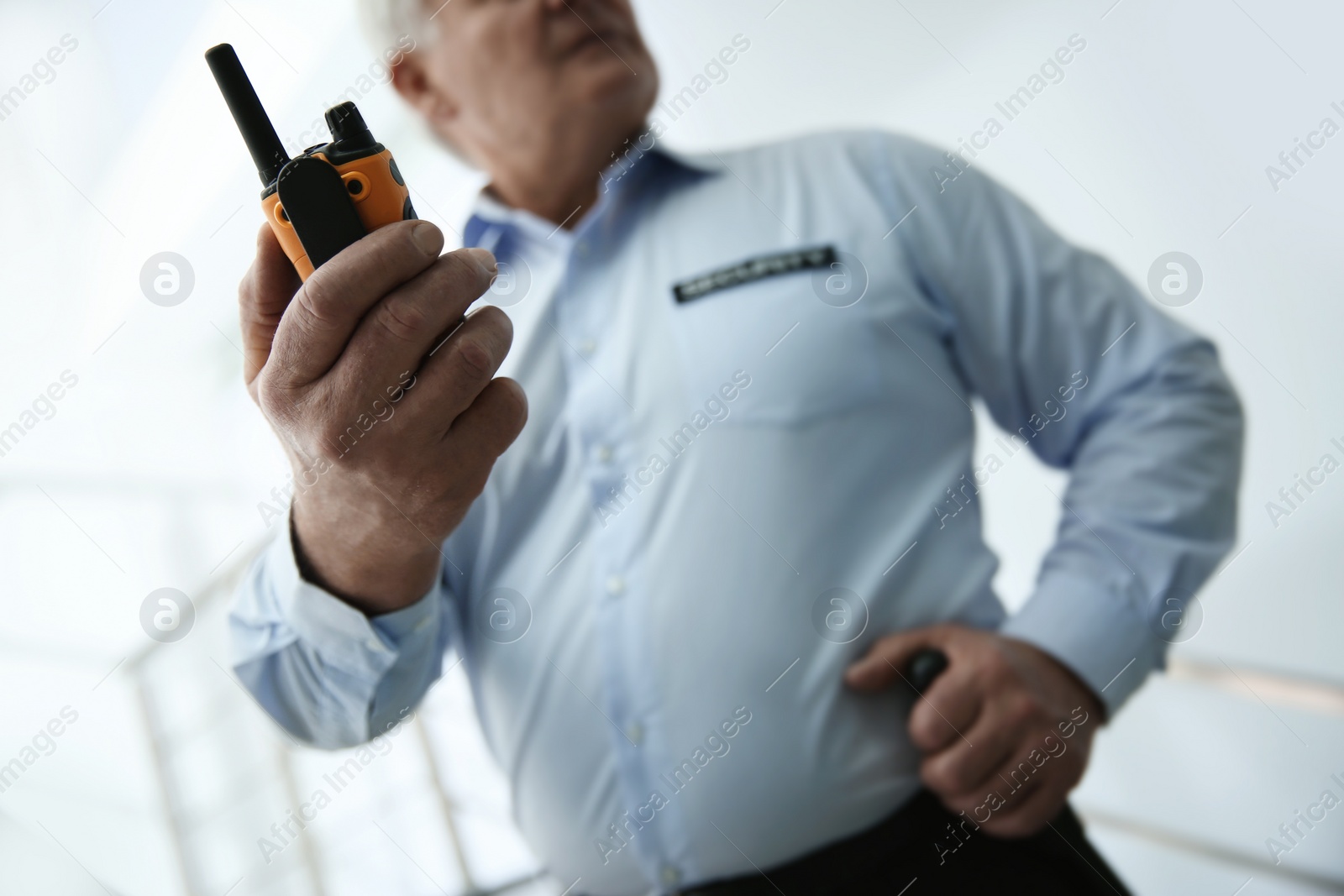 Photo of Professional security guard with portable radio set on stairs, closeup