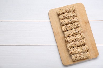 Photo of Tasty sesame seed bars on white wooden table, top view. Space for text