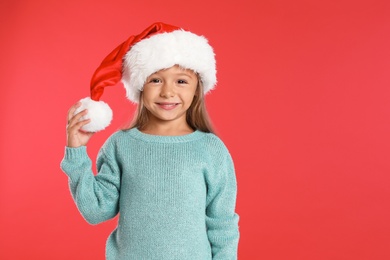 Photo of Happy little child in Santa hat on red background. Christmas celebration
