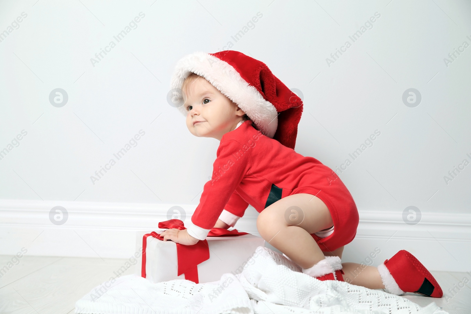 Photo of Cute little baby in Christmas costume with gift at home