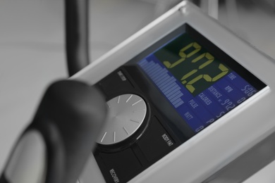 Control panel of modern elliptical machine cross trainer on blurred background, closeup