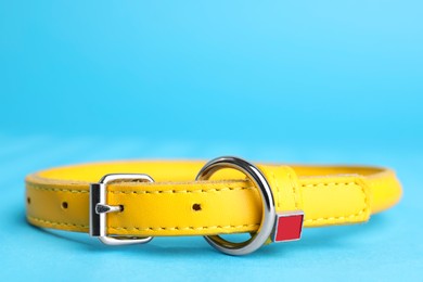 Photo of Yellow leather dog collar on light blue background, closeup. Space for text