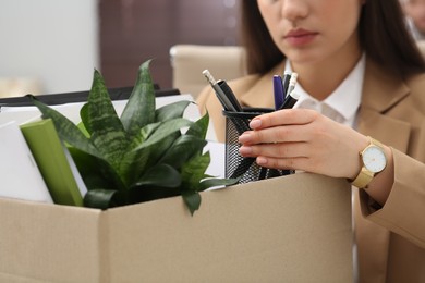 Photo of Dismissed woman packing personal stuff into box in office, closeup