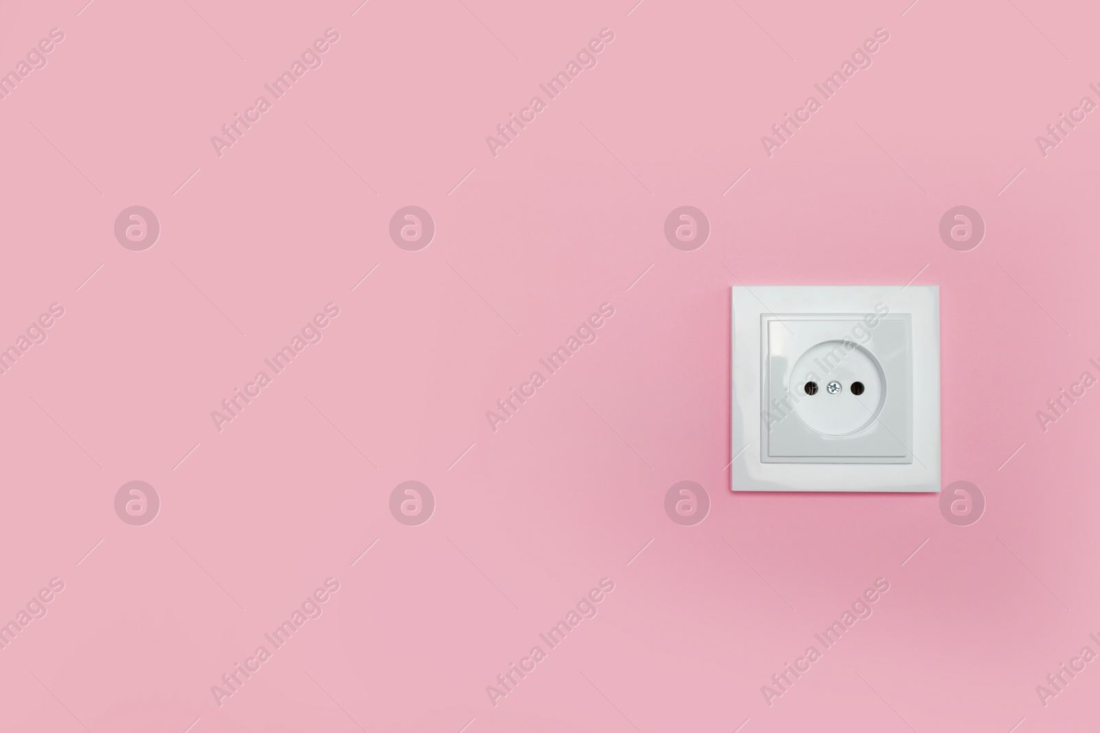 Photo of Power socket on pink wall, space for text. Electrical supply