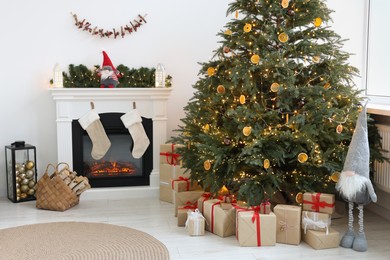 Photo of Many different gift boxes under Christmas tree and festive decor in living room