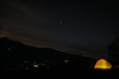 Photo of Beautiful view of mountain landscape with glowing yellow camping tent at night