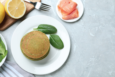 Tasty spinach pancakes served on light grey marble table, flat lay. Space for text