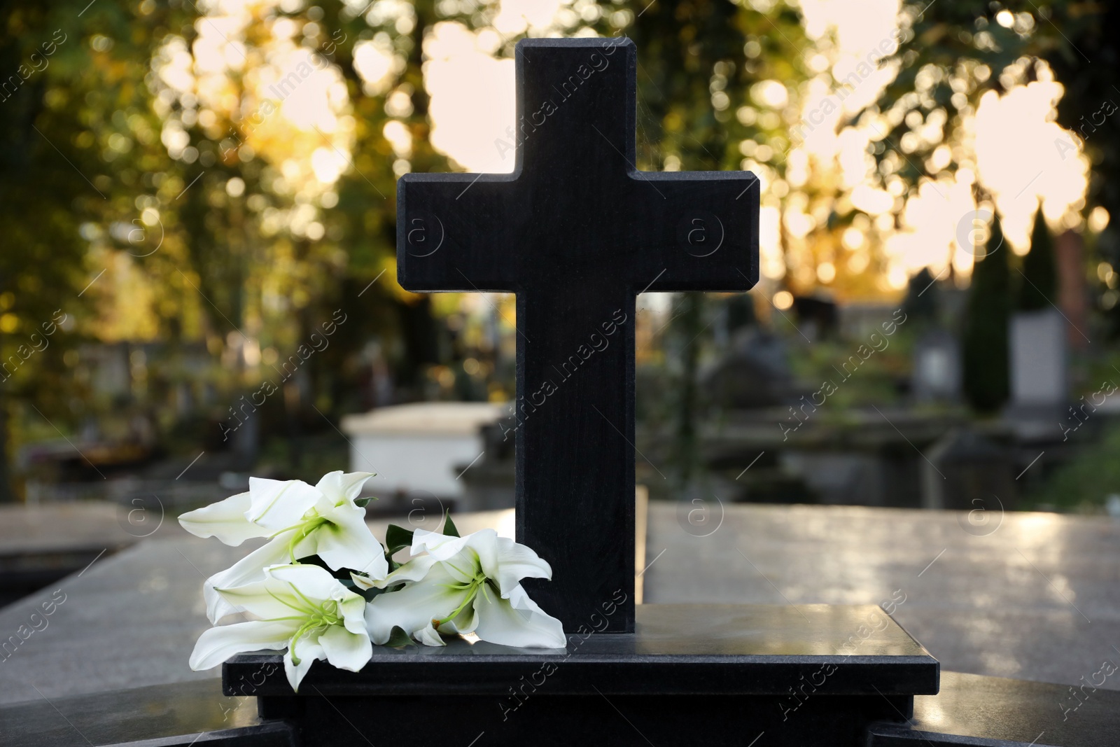 Photo of White lilies on tombstone outdoors. Funeral ceremony