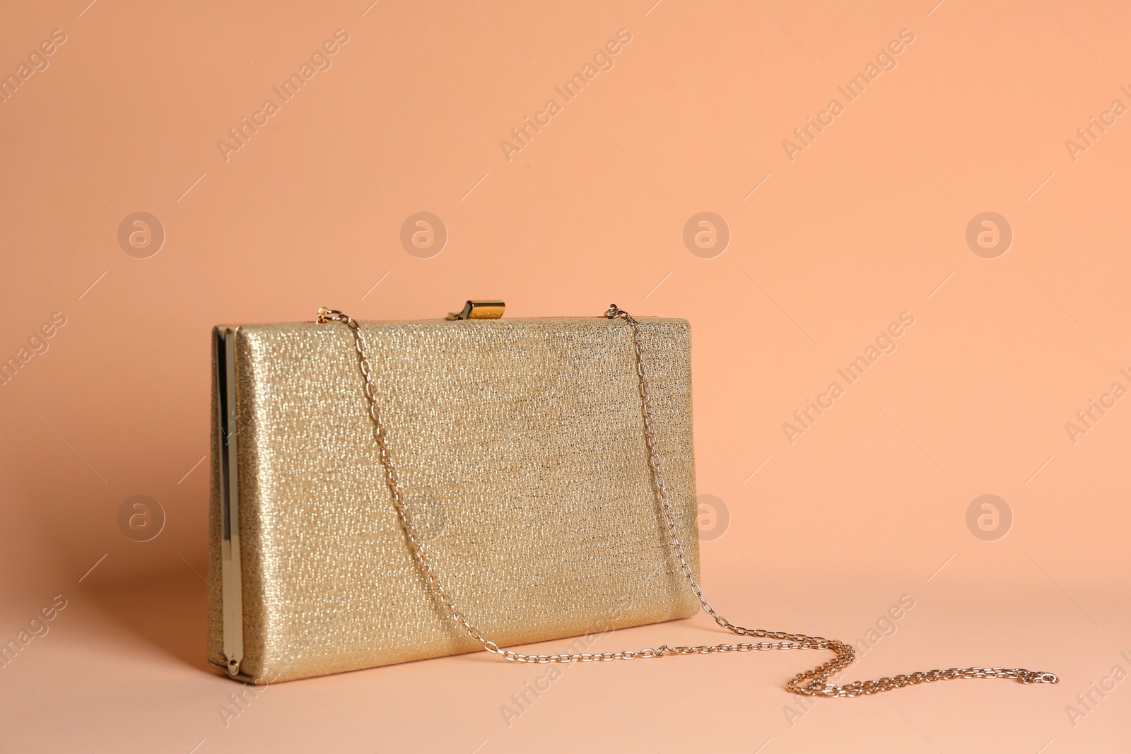 Photo of Golden stylish woman's bag on pale pink background