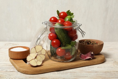 Pickling jar with fresh ripe vegetables and spices on white wooden table