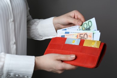 Photo of Woman holding wallet with different Euro banknotes on grey background, closeup. Money exchange