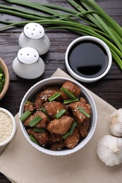 Tasty soy sauce, roasted meat and ingredients on wooden table, flat lay