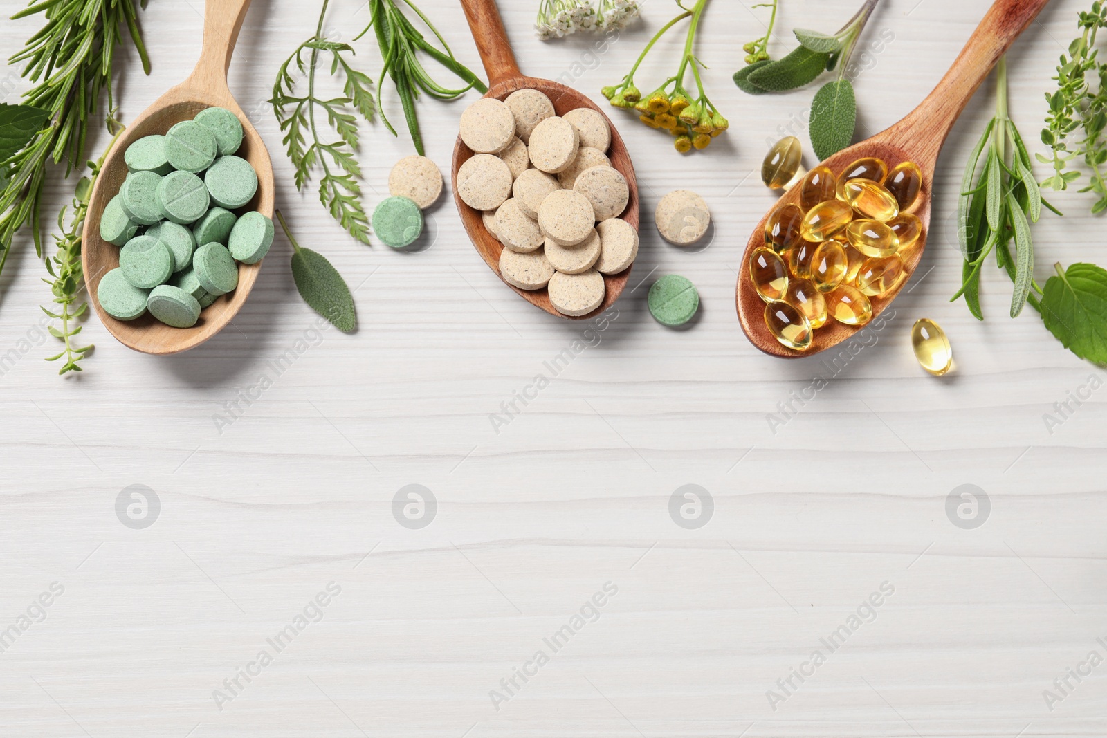 Photo of Different pills, herbs and flowers on white wooden table, flat lay with space for text. Dietary supplements