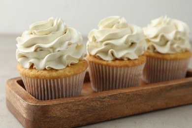 Photo of Tasty cupcakes with vanilla cream on light grey table, closeup