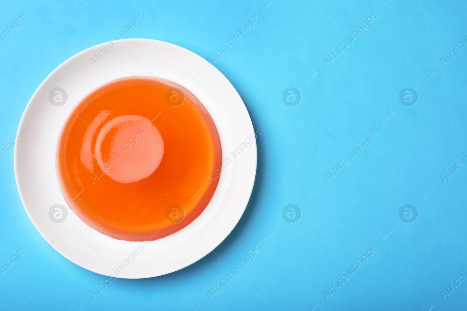 Photo of Delicious fresh orange jelly on blue background, top view. Space for text