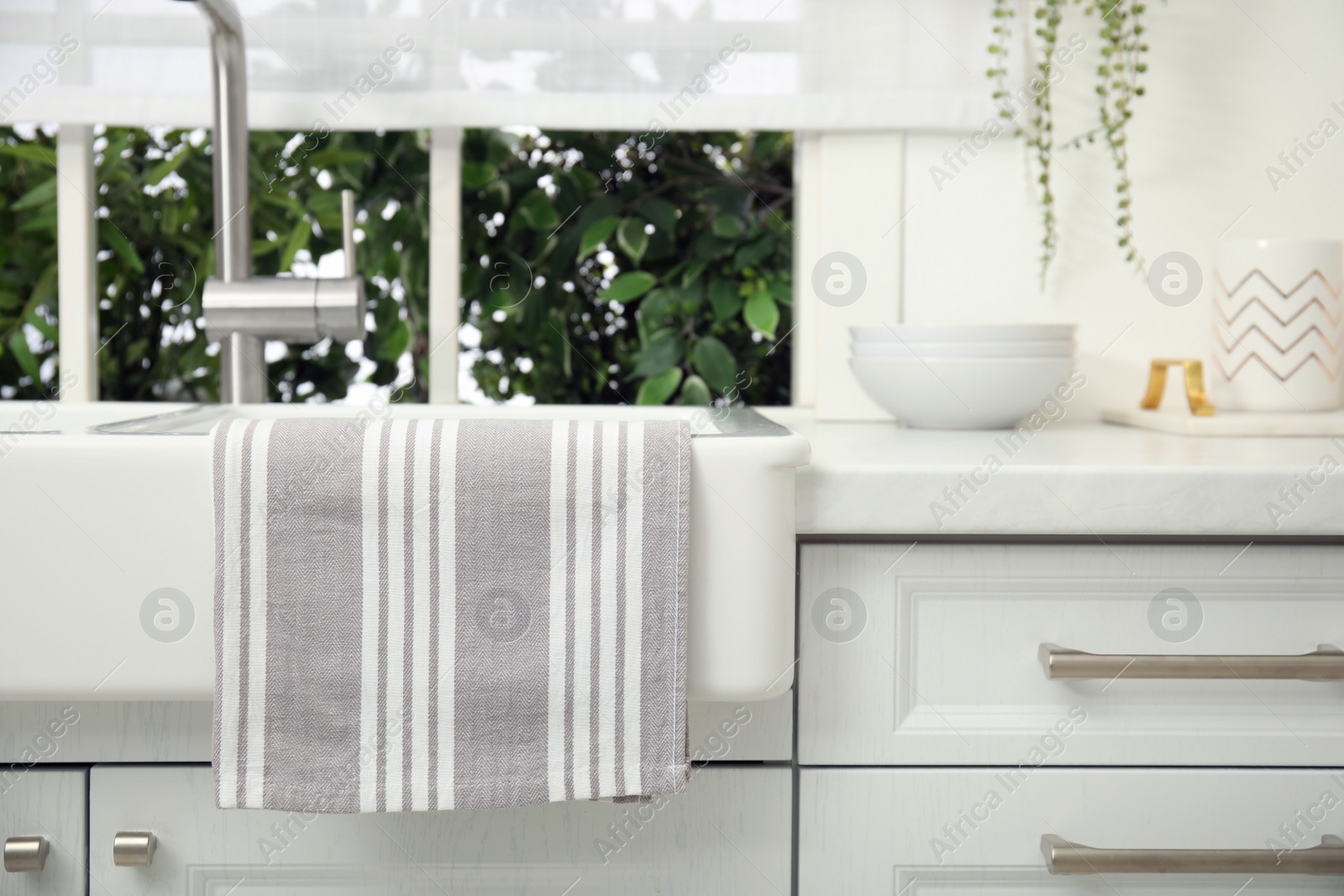 Photo of Clean towel hanging on white sink in kitchen