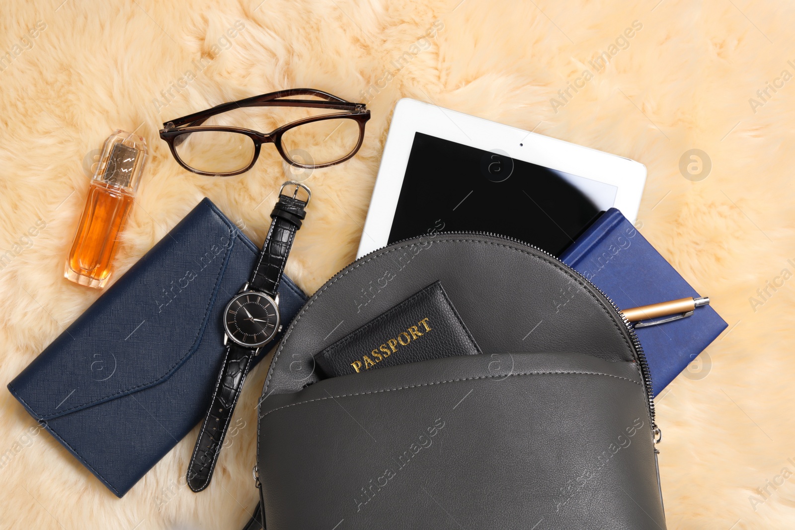 Photo of Stylish urban backpack and different items on yellow faux fur, flat lay