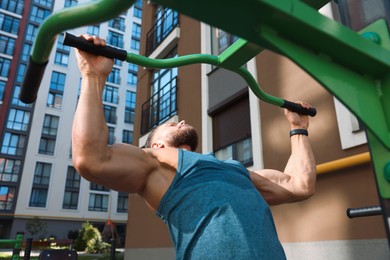 Photo of Man doing pull ups at outdoor gym, low angle view