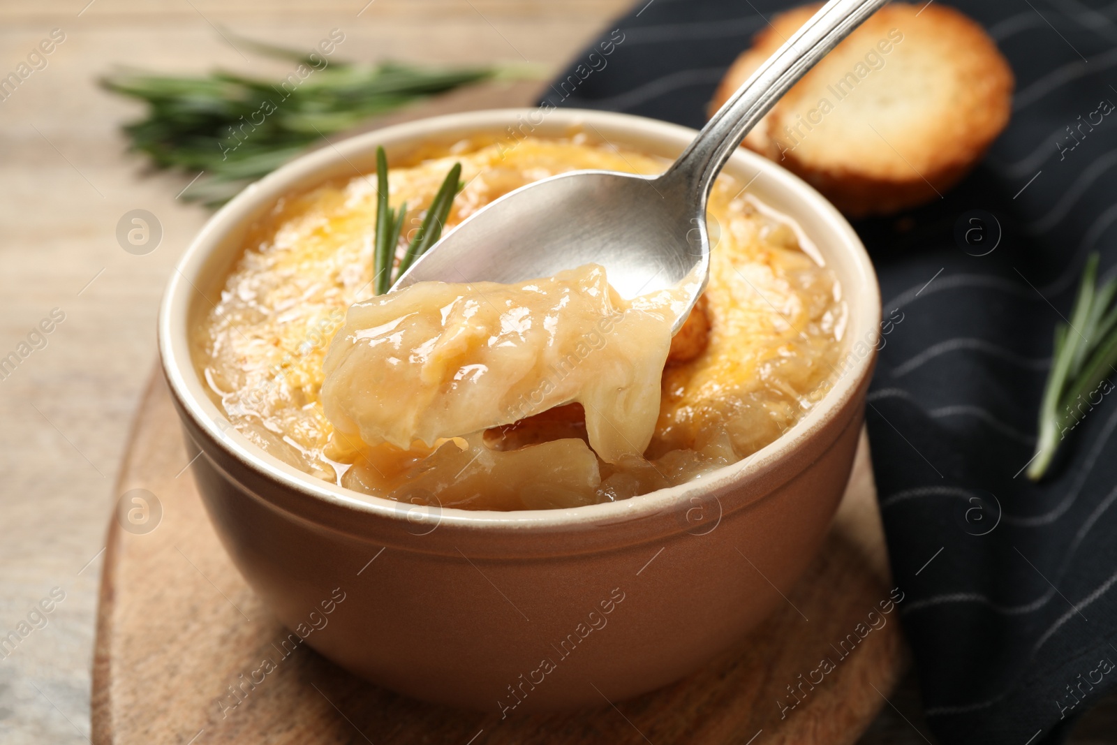 Photo of Tasty homemade french onion soup on wooden table, closeup