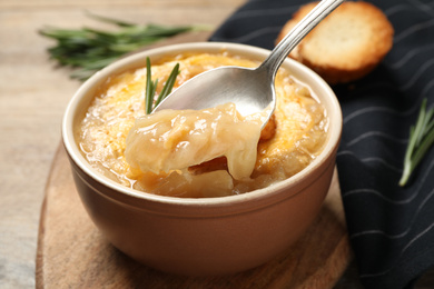 Photo of Tasty homemade french onion soup on wooden table, closeup