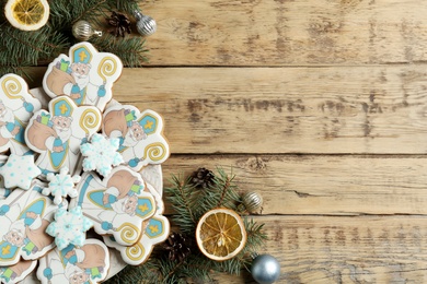 Photo of Tasty gingerbread cookies and festive decor on wooden table, flat lay with space for text. St. Nicholas Day celebration
