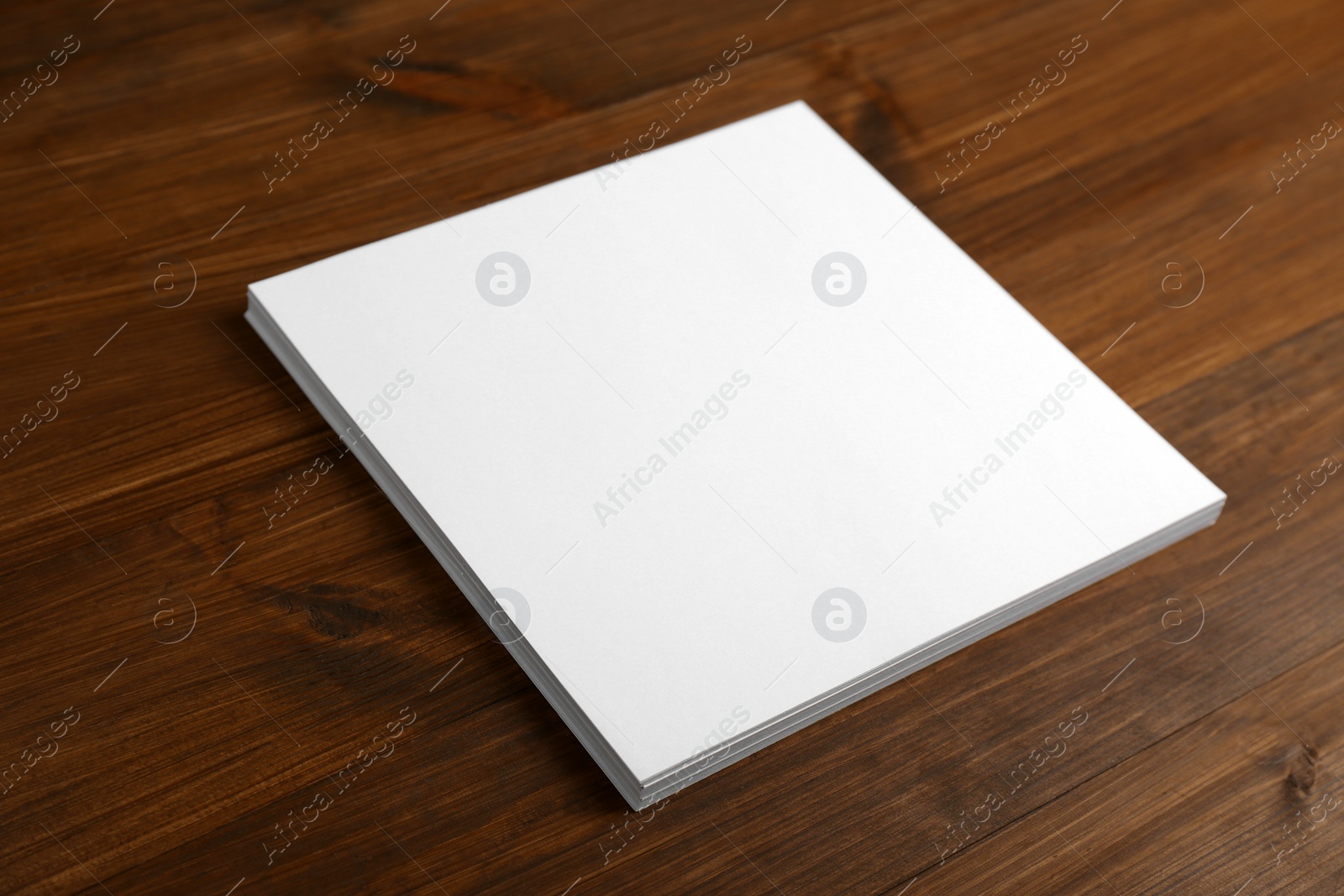 Photo of Stack of blank paper sheets on wooden table. Brochure design