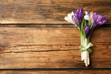 Photo of Beautiful spring crocus flowers on wooden table, top view. Space for text