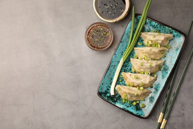 Photo of Delicious gyoza (asian dumplings) served on gray table, flat lay. Space for text