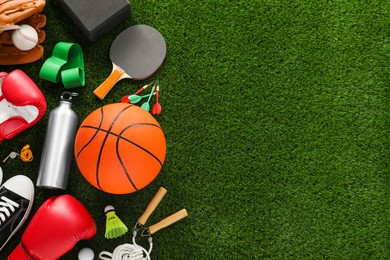 Photo of Different sport equipment on green grass, flat lay. Space for text