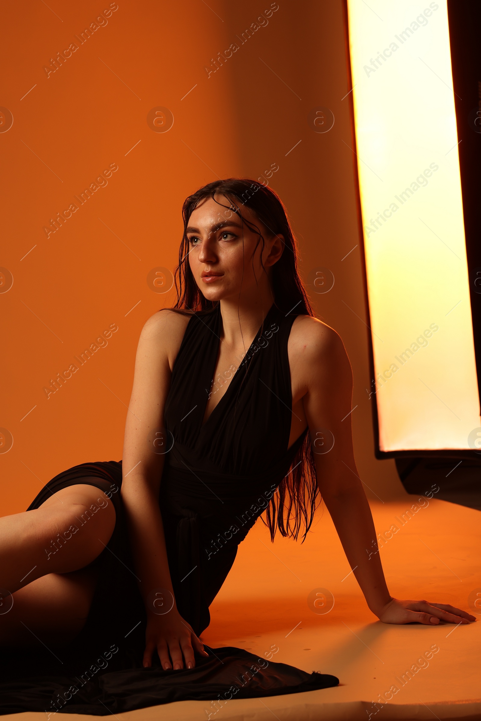 Photo of Beautiful woman in black dress posing on brown background