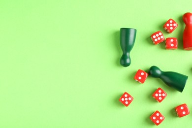 Photo of Many red dices and color game pieces on green background, flat lay. Space for text