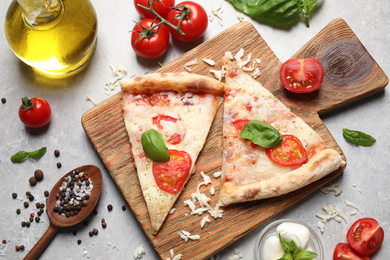 Photo of Slices of delicious pizza Margherita on light grey table, flat lay