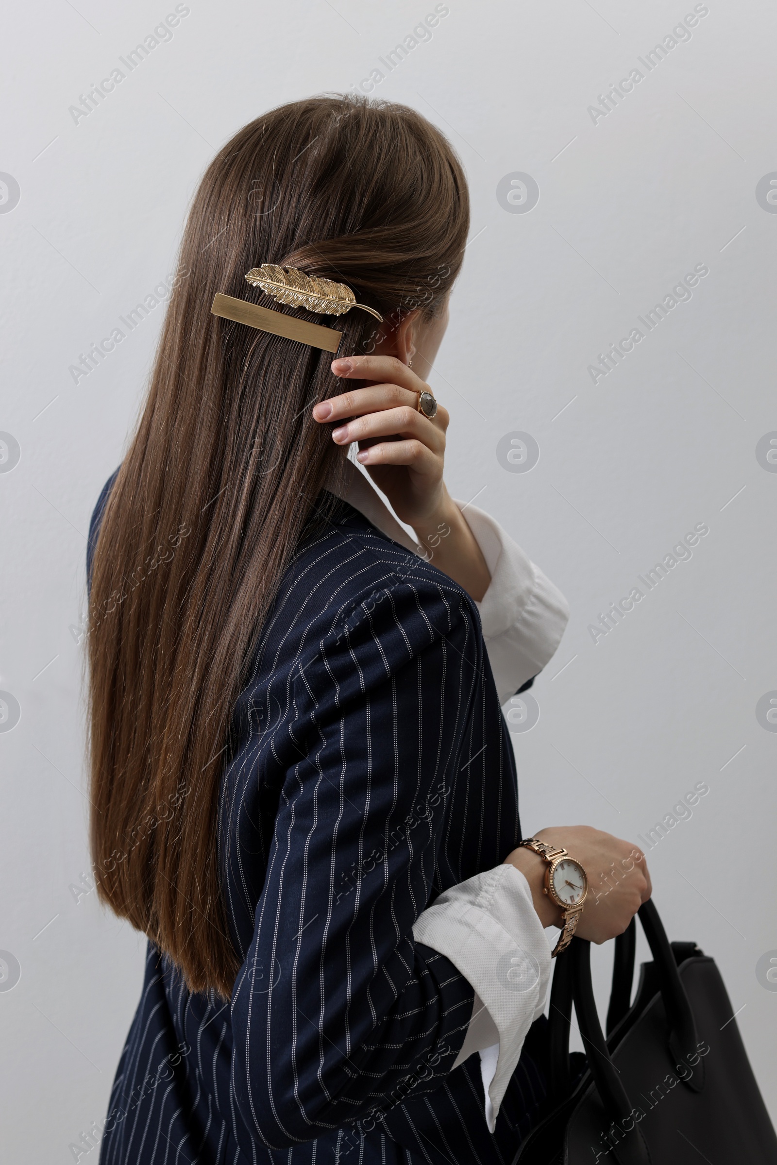 Photo of Young woman with beautiful hair clips on light background, back view